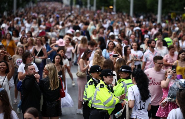 Police officers talk with fans of US mega-star Taylor Swift, so-called "Swifties", as they walk along Olympic Way outside Wembley Stadium in London on August 15, 2024, ahead of the first of five concerts she is playing at the stadium. Taylor Swift returns to the stage in London on Thursday to end the European leg of her "Eras" tour, a week after her Vienna concerts were cancelled due to a suicide attack plot. Around 90,000 fans will again pack London's Wembley Stadium for the first date in the five-day run, with additional ticket checks and restrictions in place. (Photo by HENRY NICHOLLS / AFP) (Photo by HENRY NICHOLLS/AFP via Getty Images)