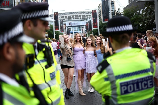 A Police officers takes a photograph of fans of US mega-star Taylor Swift, so-called "Swifties", as they gather on Olympic Way outside Wembley Stadium in London on August 15, 2024, ahead of the first of five concerts she is playing at the stadium. Taylor Swift returns to the stage in London on Thursday to end the European leg of her "Eras" tour, a week after her Vienna concerts were cancelled due to a suicide attack plot. Around 90,000 fans will again pack London's Wembley Stadium for the first date in the five-day run, with additional ticket checks and restrictions in place. (Photo by HENRY NICHOLLS / AFP) (Photo by HENRY NICHOLLS/AFP via Getty Images)